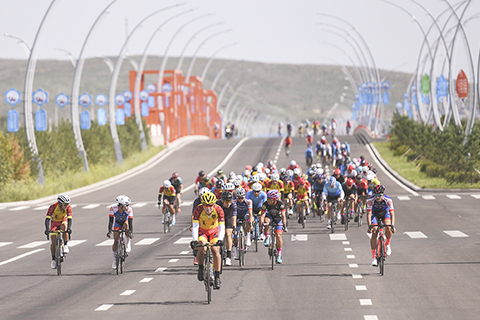 ◎ 七月二十五日,第十四屆環多倫湖公路自行車賽在內蒙古錫林郭勒盟多倫縣舉行。本屆比賽分為男女精英組(九十一公里)和男女成人組(五十公里),來自內蒙古自治區全區四十一支代表隊的一百九十四名自行車運動員和運動愛好者參與其中。圖為參賽選手在你追我趕。(新華社記者 劉磊 攝)