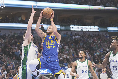 ◎ 勇士居里(三十號)上籃,遇獨行俠當錫(左)阻擋。(美聯社)