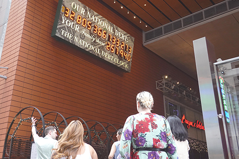 ◎ 二0二三年八月十五日,紐約曼哈頓,美國「國債鐘」顯示屏前的背影。(中新社記者王帆 攝)