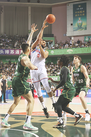 ◎ 四月七日晚,CBA季後賽中,新疆伊力特隊(白衣)客場113比108戰勝南京頭排蘇酒隊(綠衣),挺進八強。圖為新疆伊力特隊球員勞森(左二)在比賽中傳球。(中新社記者 泱波 攝)