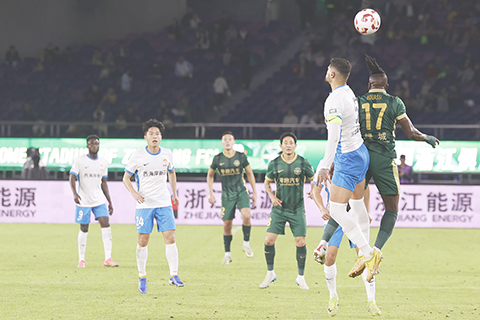 ◎ 四月二十七日晚,中國足球協會超級聯賽第九輪比賽中,浙江俱樂部綠城隊(綠)主場二比一戰勝青島西海岸隊(白)。圖為雙方球員在比賽中頭球爭頂。(中新社記者 蕭健 攝)