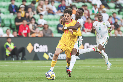 ◎ 三月三十一日,在澳大利亞墨爾本舉辦的國際足聯繫列賽中,中國隊0比二不敵喀麥隆隊(白衣)。圖為中國隊球員拜合拉木.阿卜杜外力(黃)在比賽中突破遇阻。(中新社發 祁安迪 攝)